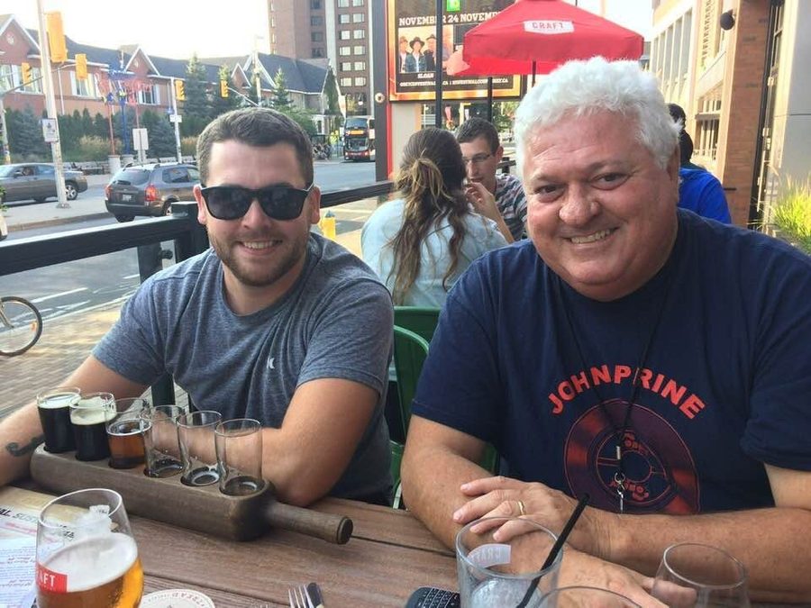 Ron with a beer flight, wearing a John Prine shirt