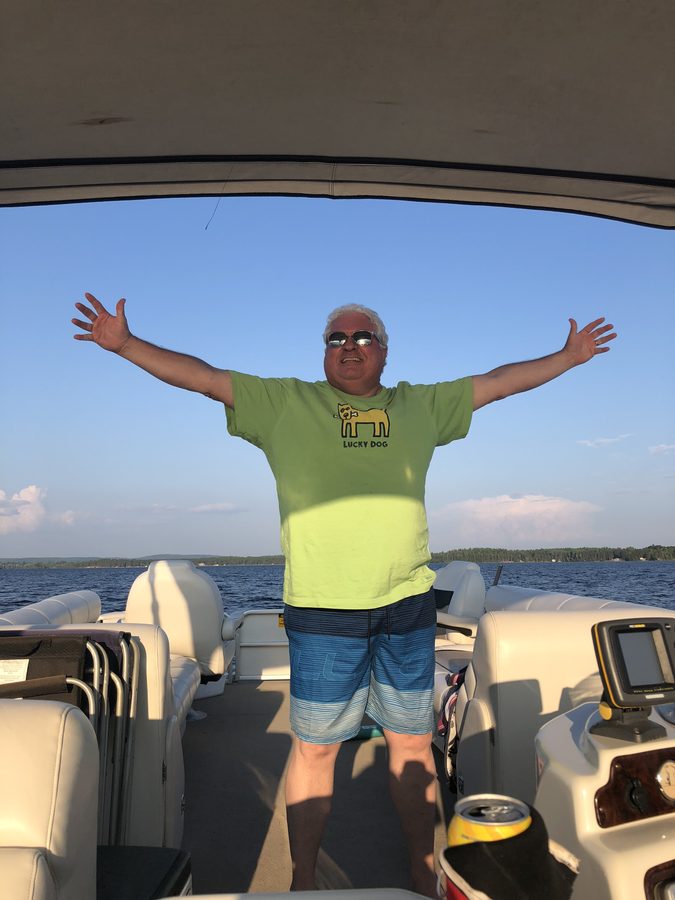 Ron standing with his arms wide on the pontoon boat