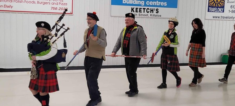 Curlers follow a piper onto the ice at the Killaloe Curling Club, Ron among them