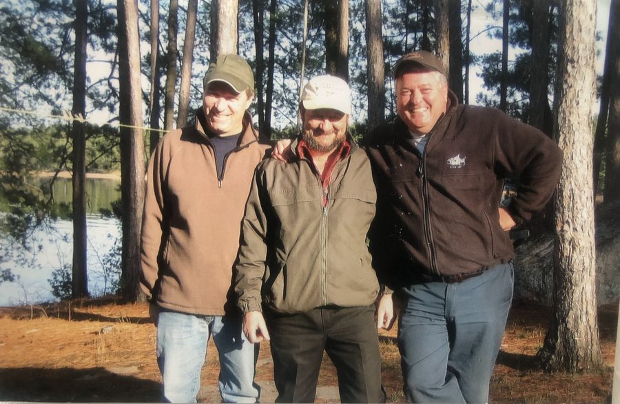 Ron with two friends among the pines by the water